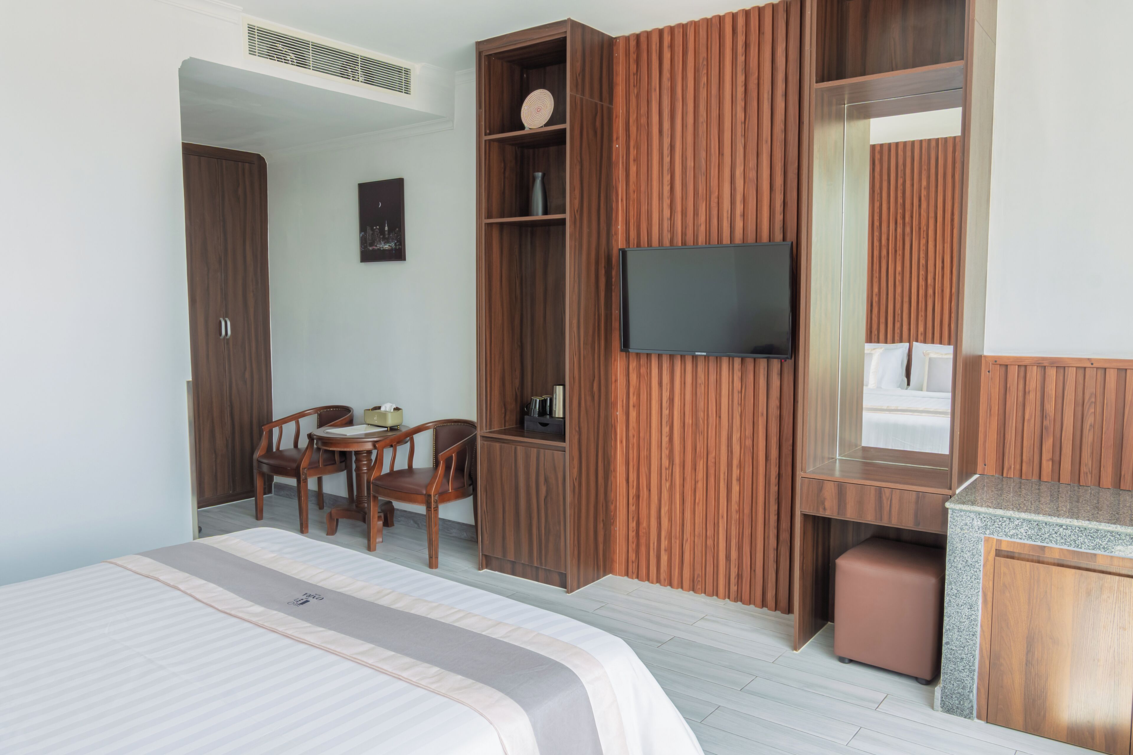Une chambre d’hôtel moderne équipée d’un lit, d’un bureau, d’une chaise, d’une télévision et d’une armoire.