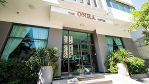 The exterior of The Onra Hotel with large windows, a modern facade, and potted plants in front. - The ONRA Hotel (Phnom Penh)
