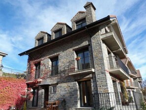 A stone building with multiple balconies and a small patio area.