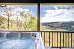 Een jacuzzi met uitzicht op een bebost landschap en bergen.