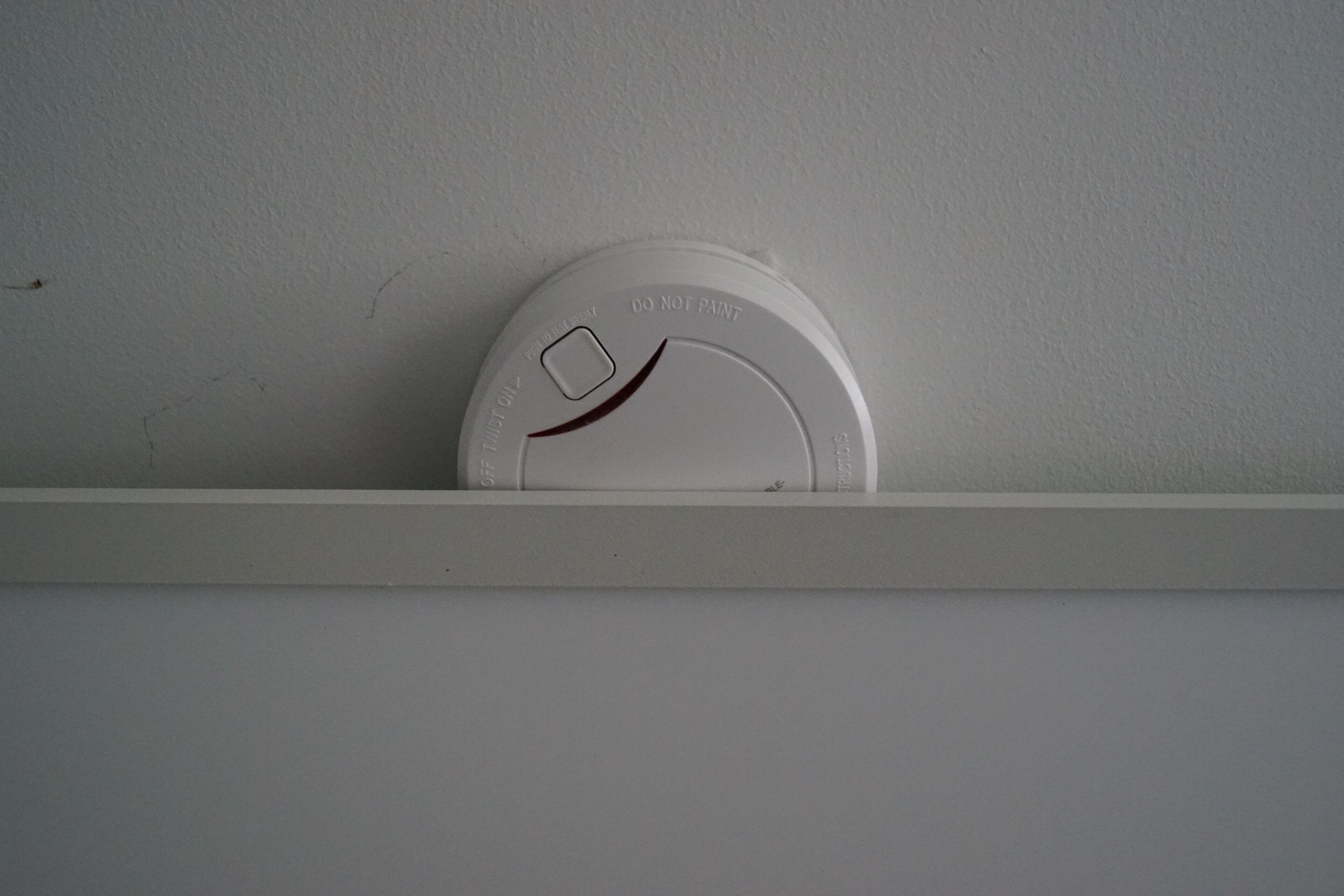 Ein weißer Rauchmelder an einer Wand befestigt.
