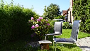 A garden with a bench and a small table, surrounded by lush greenery and flowers.