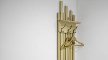 A wooden bench and a wall-mounted rack with hooks and a hanger.