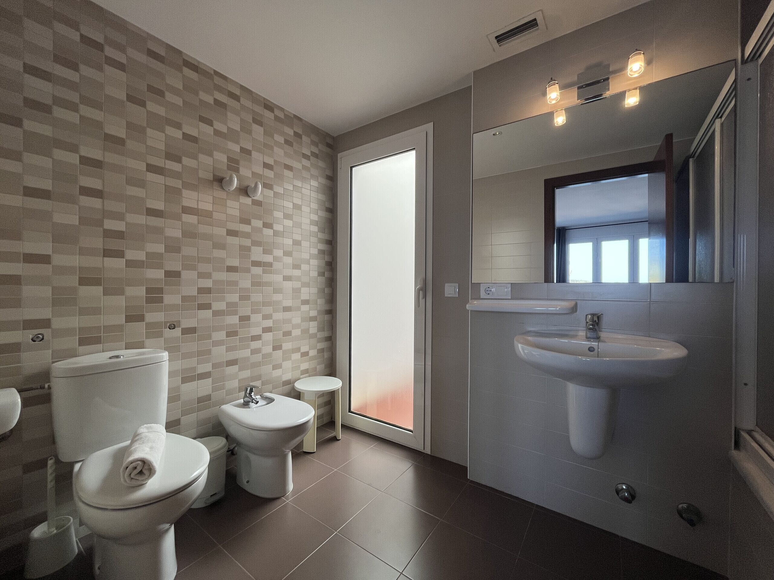 Een moderne badkamer met toilet, hygiëneschuimer en wastafel.
