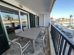 Un balcon avec une table et des chaises, une vue sur la rue et une balustrade.