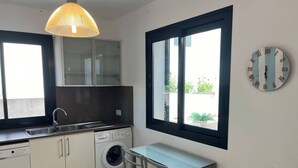 Ett modernt kök med tvättmaskin, matbord och ett stort fönster.