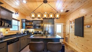 A modern kitchen with wooden walls, stainless steel appliances, and a central island with bar stools.