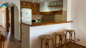 Une cuisine dotée d’un plan de travail en bois, d’un réfrigérateur, d’un four à micro-ondes et d’un luminaire suspendu.