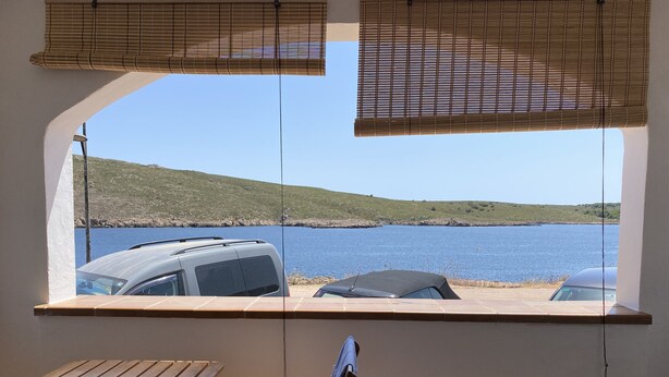 Une pièce avec vue sur un plan d’eau, une table et deux chaises.