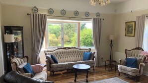Een woonkamer met een bank, fauteuils, een salontafel en een vloerkleed.
