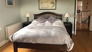 Een slaapkamer met een bed, twee nachtkastjes, een radiator en een schilderij aan de muur.