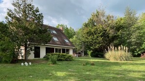 A house with a sloped roof, surrounded by a well-maintained lawn and trees.