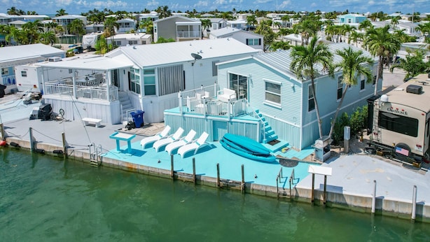 Une maison située au bord de l’eau, dotée d’une piscine, d’une terrasse couverte et d’un quai pour bateaux.