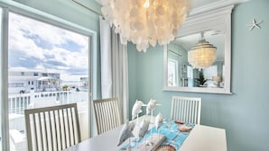 Un espace repas avec vue sur la plage, un lustre et une table agrémentée d’objets décoratifs.