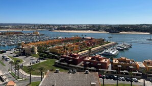 Un puerto deportivo con barcos, una playa y edificios con vistas claras a la costa.