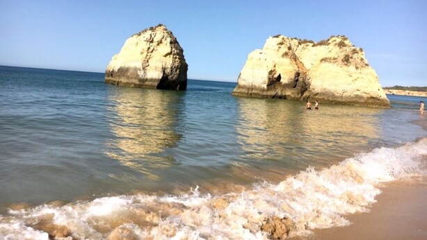 Una playa con dos grandes formaciones rocosas en el agua.