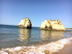 Ein Strand mit zwei großen Felsformationen im Wasser.
