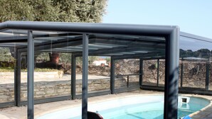 A covered outdoor swimming pool with stone walls and a clear view of the surrounding landscape. - Villa for 10 people with swimming pool. (Montpeyroux)