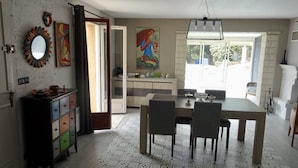 A dining area with a table and chairs, a cabinet with multiple drawers, a mirror, and a painting on the wall. - House with pool next to lake Saint-Cassien in the Esterel valleys. 20 min Cannes (Montauroux)