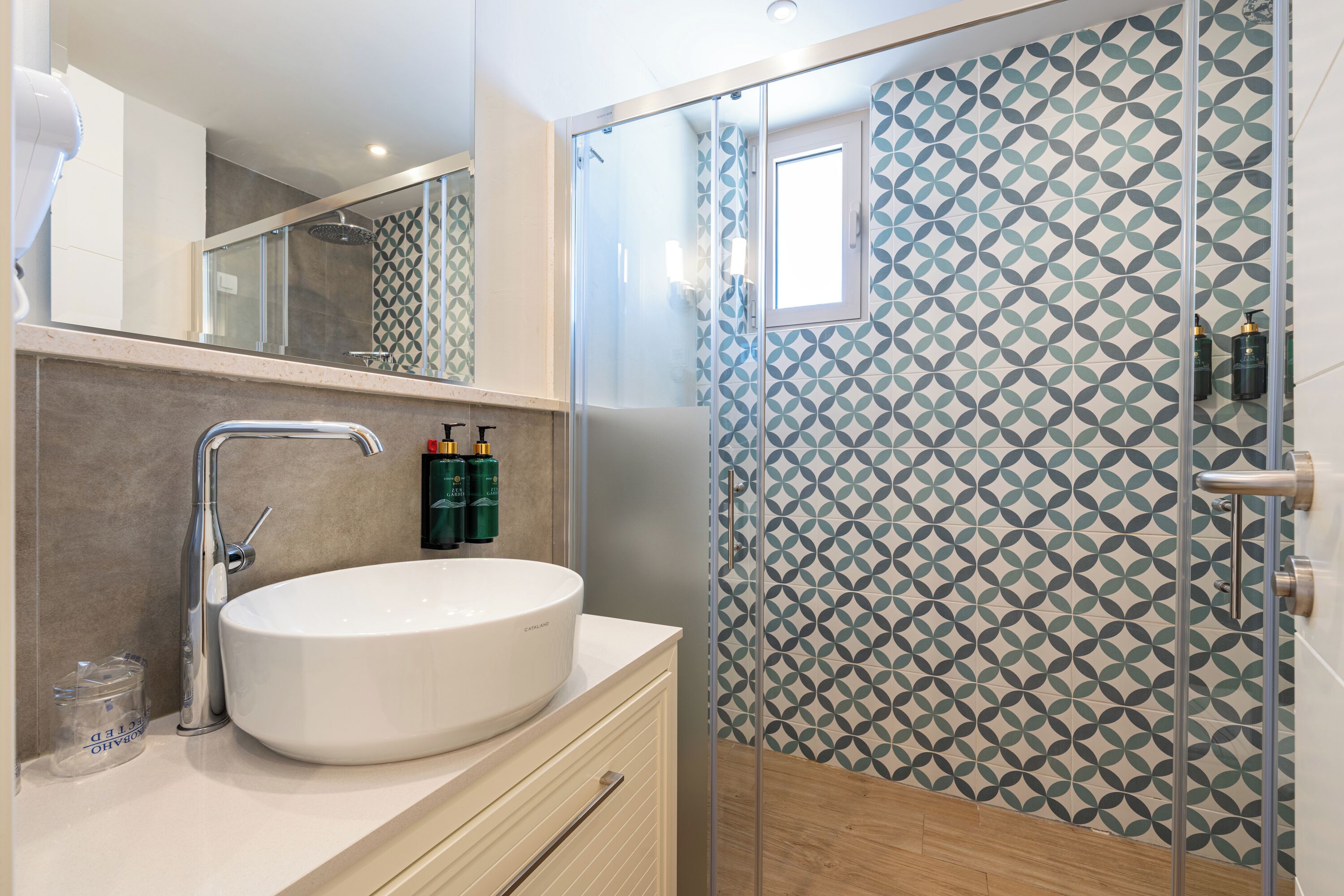 Een moderne badkamer met een groot wit wastafelmeubel, een douchecabine van glas en betegelde wanden.