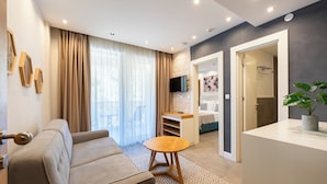 A modern living room with a sofa, a small wooden table, a TV, and a plant.