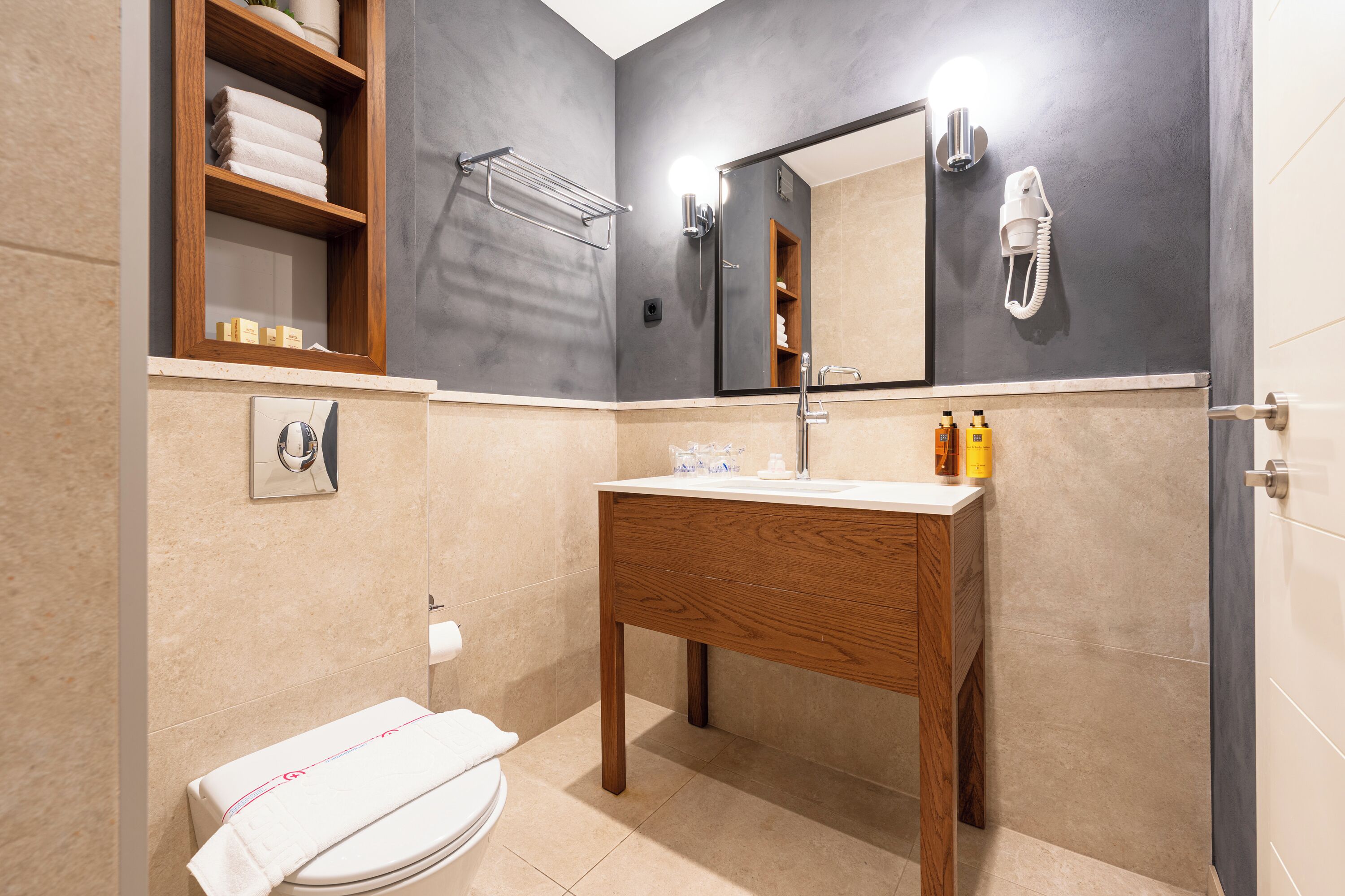 A modern bathroom with a wooden vanity, a towel rack, a mirror, and a toilet.