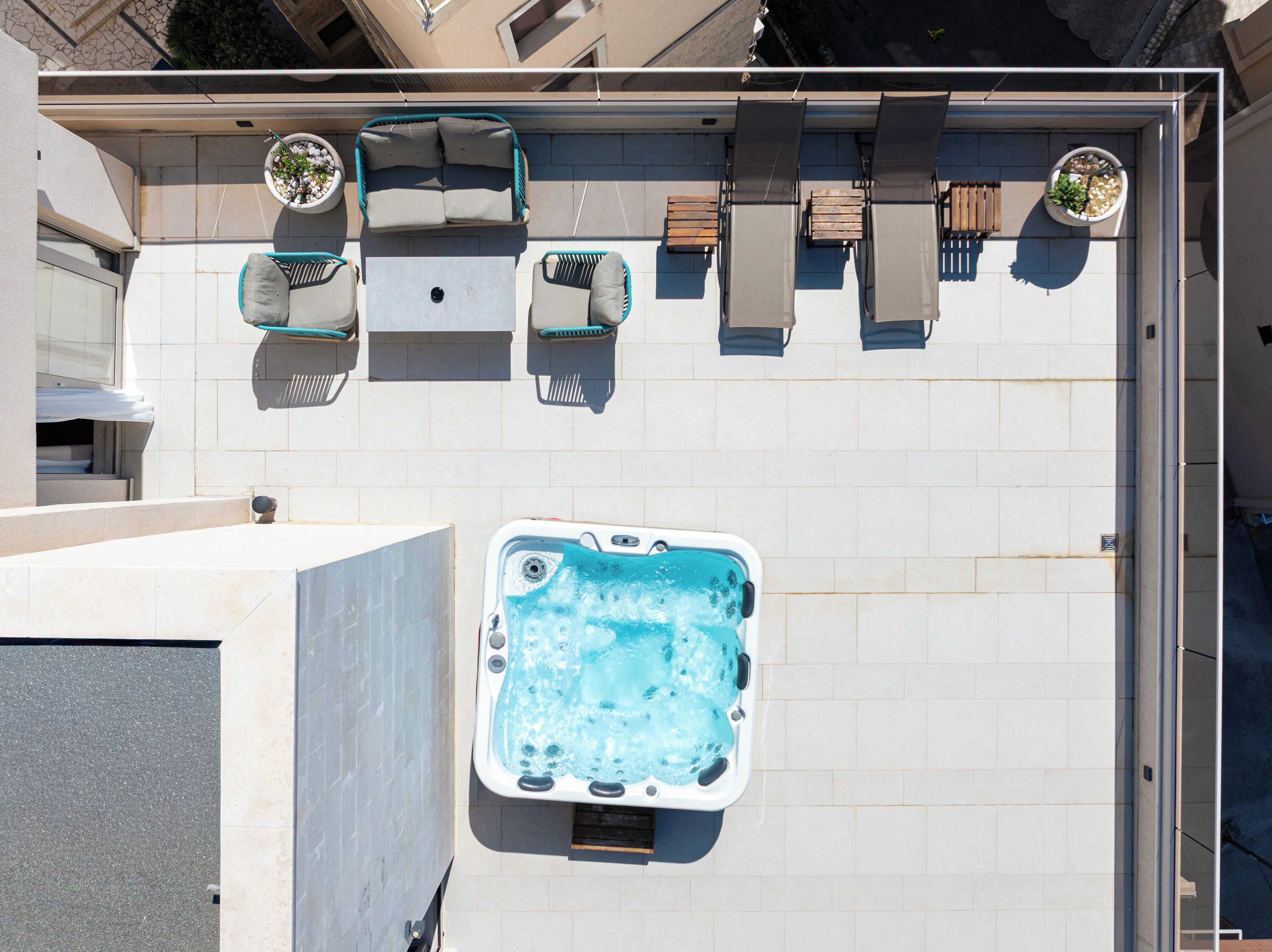 Une terrasse sur le toit avec un jacuzzi, des sièges d’extérieur et des plantes en pot.