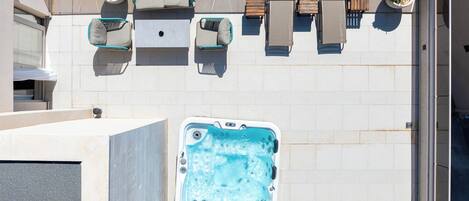 Une terrasse sur le toit avec un jacuzzi, des sièges d’extérieur et des plantes en pot.