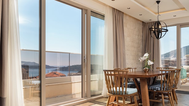 A dining area with a table and chairs, a chandelier, and a view through large glass doors.