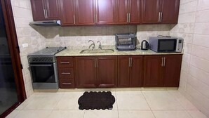 Una cocina compacta con armarios de madera, cocina a gas, microondas y lavabo.