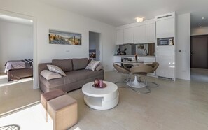 A modern living room with a sofa, ottomans, and a dining area with chairs and a table. - Caci-A1 with Pool - istriensonne 0712 (Medulin)