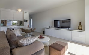 Uma sala de estar moderna com um sofá, mesa de centro e televisão fixada na parede.