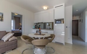 A modern hotel room with a dining area, kitchenette, and a separate living space. - Caci-A1 with Pool - istriensonne 0712 (Medulin)