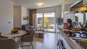 En modern lägenhet med matplats, soffa, balkong med utsikt och ett kök med moderna vitvaror.
