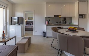 A modern kitchen with a dining area, a TV, and a bed in the background. - Caci-A2 with Pool - istriensonne 0713 (Medulin)