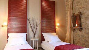 A double room with two beds, each with a red blanket, white linens, and wooden headboards. There are bedside lamps and a small table with a vase between the beds. - Enjoy the seaside living in a centraly located, pretty sea view house (Stoupa)