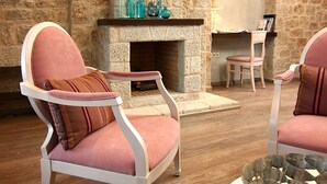 A room with stone walls, a fireplace, two pink armchairs, and a round table with a metal bowl. - Enjoy the seaside living in a centraly located, pretty sea view house (Stoupa)