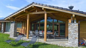 A modern house with a covered patio, stone pillars, and a dining area with outdoor furniture.