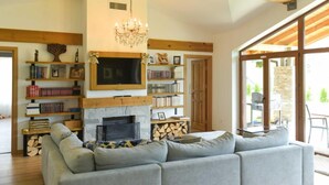 A cozy living room with a fireplace, bookshelves, a large sofa, and a dining area with a view.