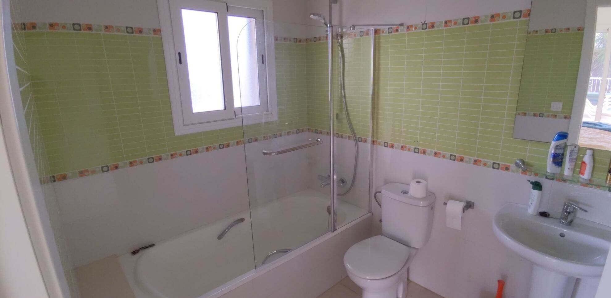 Un baño con ducha de vidrio, inodoro y lavabo.