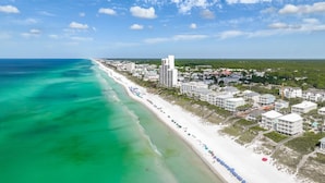 A coastal cityscape with a beach, high-rise buildings, and a clear sky.