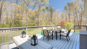 Une terrasse en bois, aménagée avec du mobilier d’extérieur, notamment des chaises et une table, et offrant une vue sur une zone boisée.