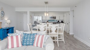 A bright, white interior with a dining area, kitchen, and a blue cabinet.