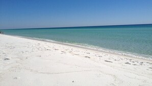 A beach with white sand and clear blue water.