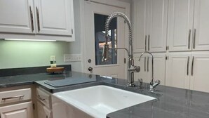 Cucina con mobili bianchi, lavandino bianco e piano di lavoro nero.