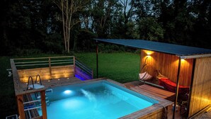 Een houten kuip met een houten terras en een kleine aanleunhut met een rood dak.