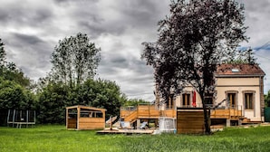 Een gebouw in aanbouw met een houten terras en lounge fauteuils.
