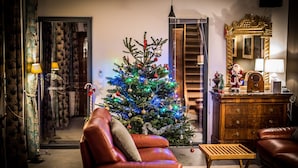 Een gezellige woonkamer met een kerstboom, een leren fauteuil, een houten salontafel en een dressoir met spiegel.