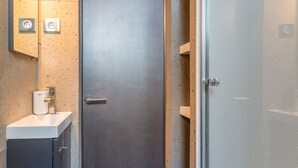 A modern bathroom with a dark door, a sink with a mirror, and a shower area. - LOFT ON THE BANKS OF THE LOIRE (Montlouis-sur-Loire)