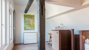 A bedroom with a wooden ceiling, a desk with a lamp, a bed with a striped bedspread, and a painting on the wall. - LOFT ON THE BANKS OF THE LOIRE (Montlouis-sur-Loire)